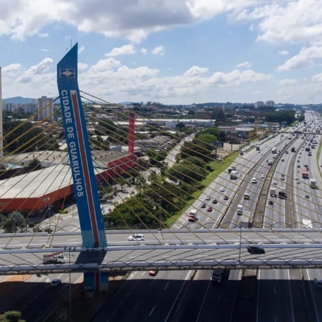 Vista aérea da ponte estaiada e rodovia movimentada sob céu nublado.