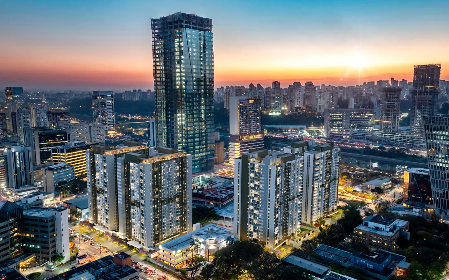 Vista aerea noturna da cidade com torres residenciais e edificios altos.