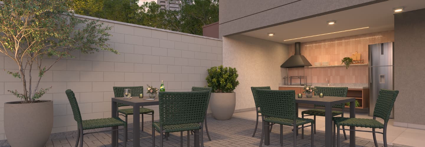 Area gourmet externa com churrasqueira, bancada e mesas com cadeiras verdes